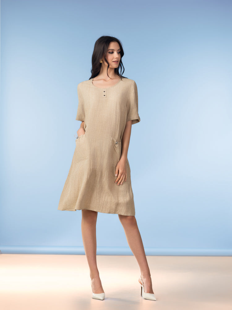 Images show the Alison Sheri Relaxed Pocket Dress A47072 in Sand and Indigo from the front and side, highlighting the round neckline, relaxed fit, elbow-length sleeves, side pockets with gentle cinching effect, and the fluid drape of the lightweight linen-blend fabric.