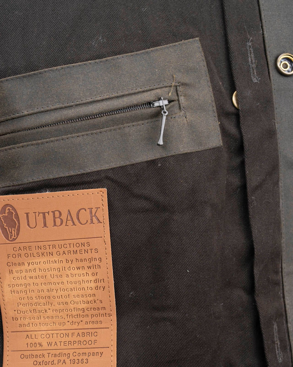 Outback Trading Company Bush Ranger Jacket in brown - showcasing its rugged oilskin texture, heavy-duty metal buttons, adjustable cuffs, and traditional Western styling. Photos include front, back, side, and close-up views of fabric and stitching details to emphasize quality and authenticity.