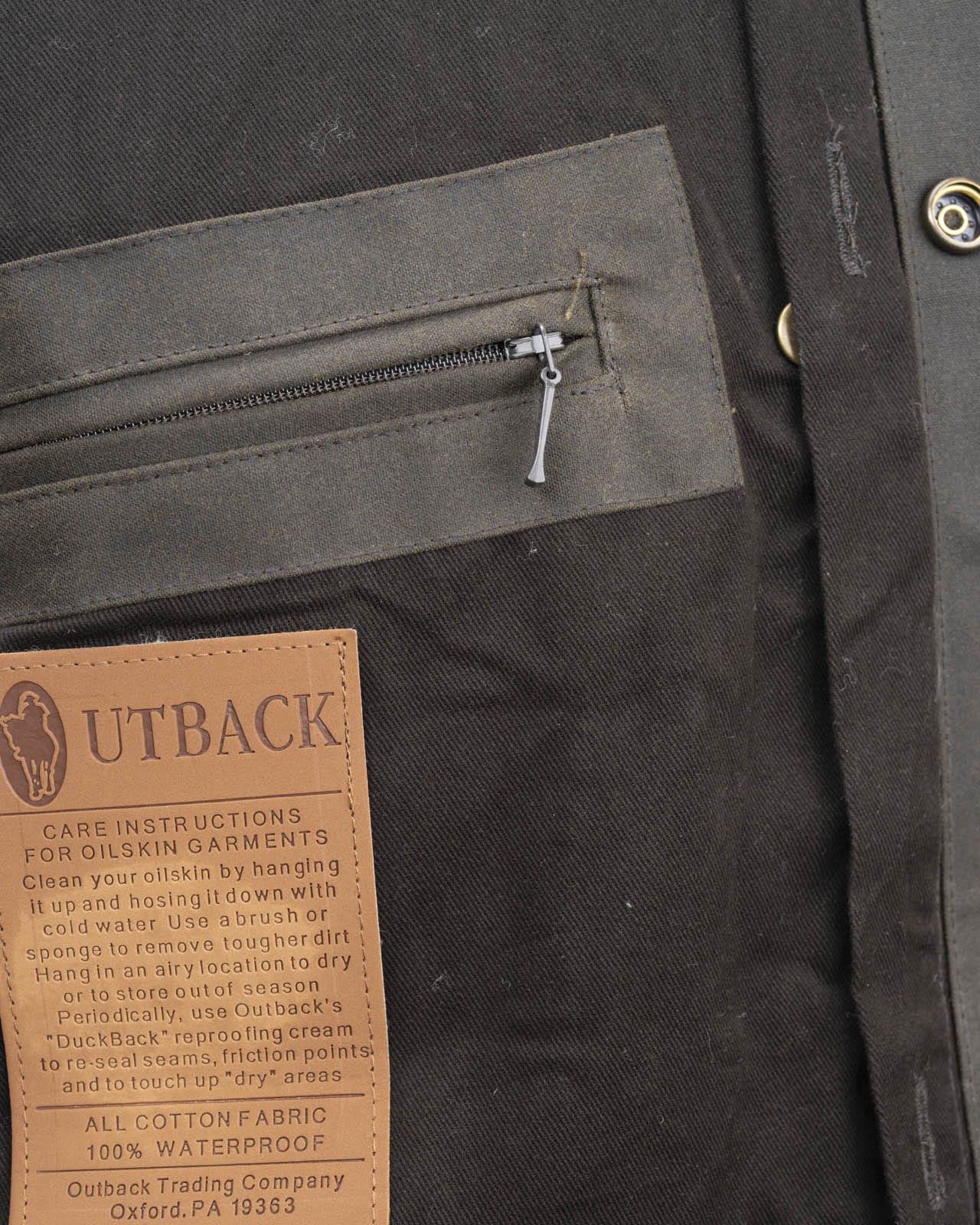 Outback Trading Company Bush Ranger Jacket in brown - showcasing its rugged oilskin texture, heavy-duty metal buttons, adjustable cuffs, and traditional Western styling. Photos include front, back, side, and close-up views of fabric and stitching details to emphasize quality and authenticity.