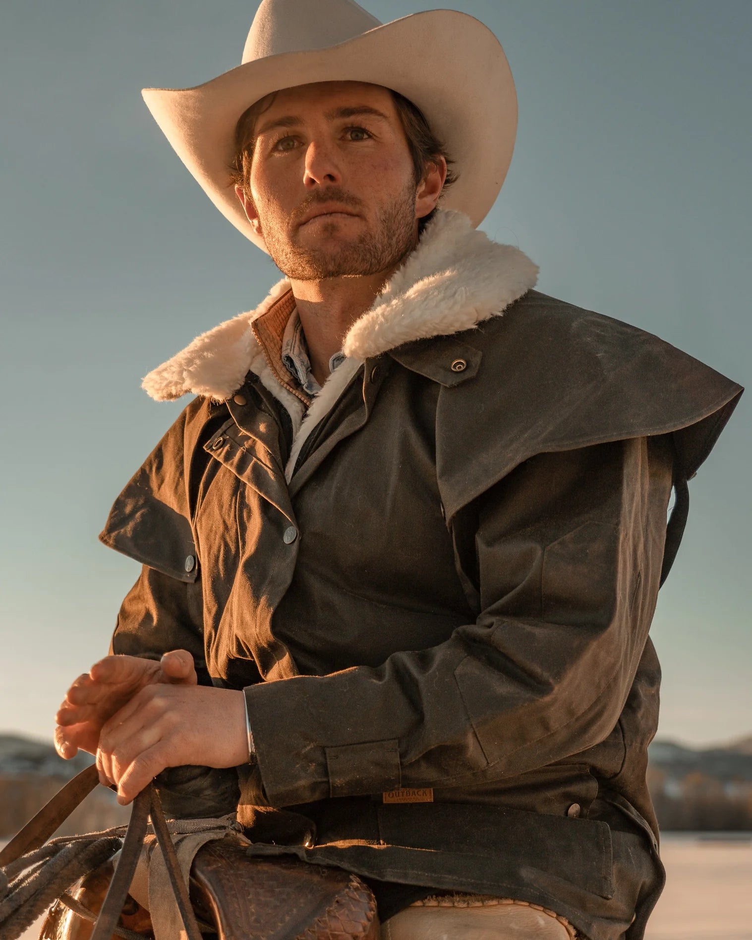 Outback Trading Company Bush Ranger Jacket in brown - showcasing its rugged oilskin texture, heavy-duty metal buttons, adjustable cuffs, and traditional Western styling. Photos include front, back, side, and close-up views of fabric and stitching details to emphasize quality and authenticity.