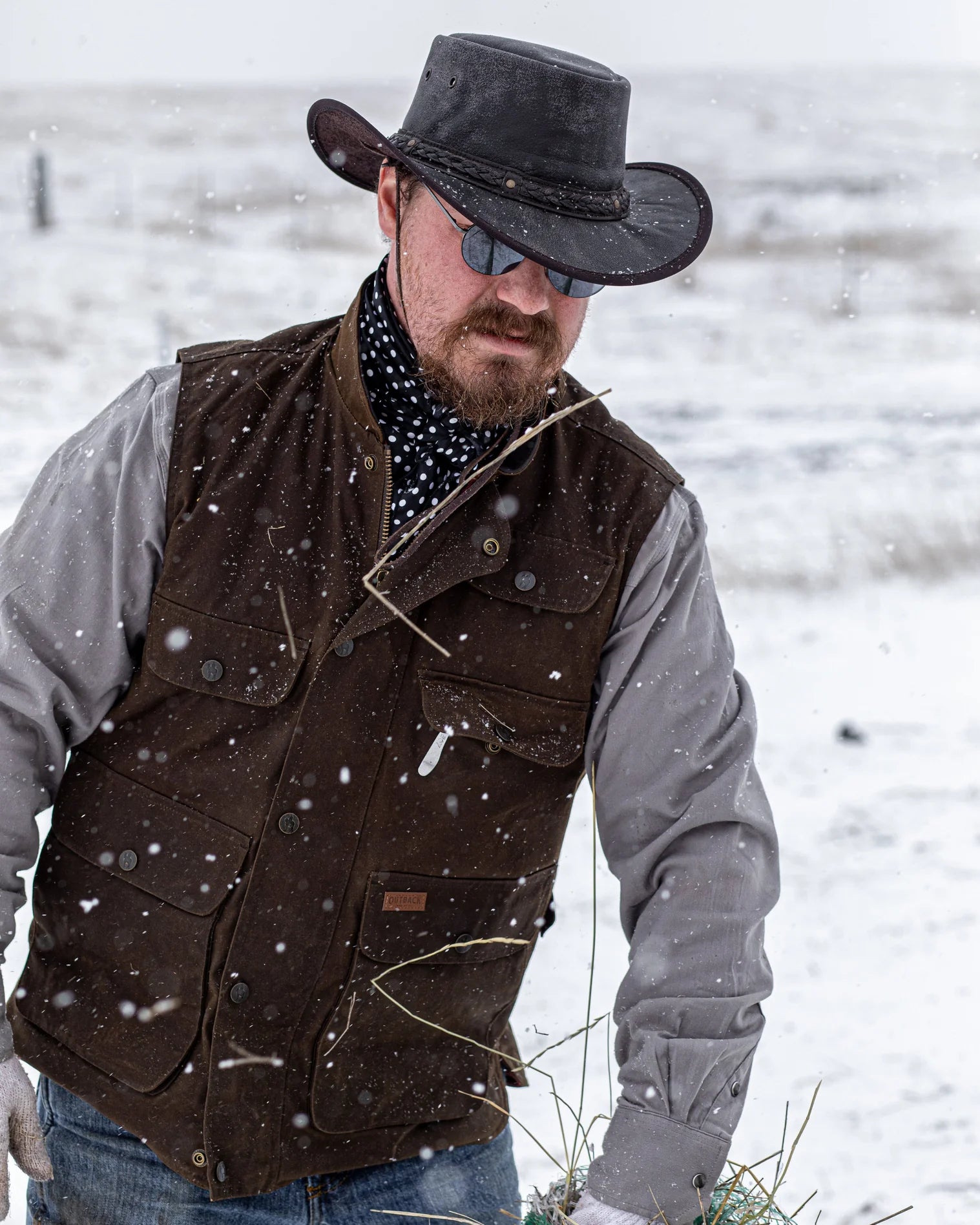 Men's Overlander Vest by Outlander Trading Co. showcasing its rugged water-resistant fabric, front zip and snap closure, multiple pockets, and adjustable side tabs. Views include front, back, and close-up shots highlighting functional details and sturdy craftsmanship.